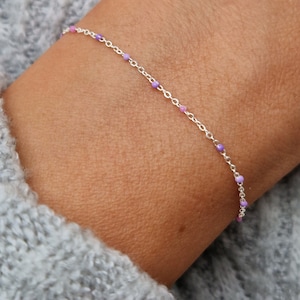 Könnte beinhalten: Ein silbernes Kettenarmband mit kleinen lila und rosa Perlen.
