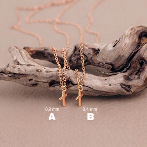 May include: Two rose gold-toned necklaces with small cross pendants. Necklace A features a 0.9 mm chain, while necklace B features a 0.4 mm chain. Both necklaces are displayed together, showcasing the difference in chain thickness for each piece.