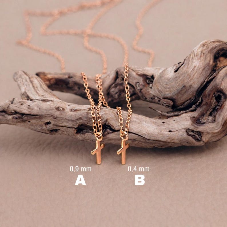 May include: Two rose gold-toned necklaces with small cross pendants. Necklace A features a 0.9 mm chain, while necklace B features a 0.4 mm chain. Both necklaces are displayed together, showcasing the difference in chain thickness for each piece.