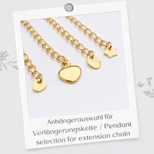 Puede incluir: Cuatro cadenas de extensi&oacute;n de metal dorado, cada una con un dije distinto en el extremo. Los dijes incluyen un coraz&oacute;n peque&ntilde;o, un coraz&oacute;n grande, un disco redondo y una estrella de cinco puntas. El texto dice: Anh&auml;ngerauswahl f&uuml;r Verl&auml;ngerungskette / Pendant selection for extension chain.