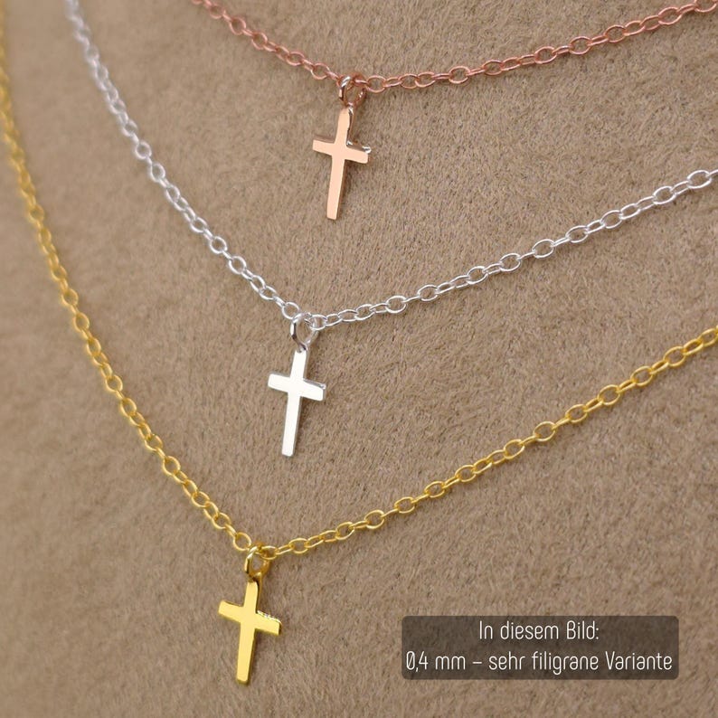 May include: Three delicate necklaces featuring small cross pendants in rose gold, silver, and gold tones. Each necklace has a fine chain link design. The text in the image indicates a 0.4 mm thickness for this specific filigree variant.