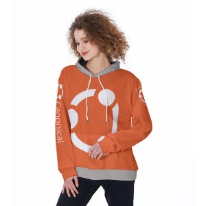 Peut inclure: Un sweat à capuche orange avec un logo blanc et le mot "Canonical" imprimé verticalement sur la manche gauche. Le sweat à capuche a une doublure de capuche grise et des cordons de serrage. La personne porte un pantalon noir.