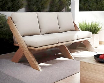 Może przedstawiać: Trzyosobowa drewniana sofa z jasnobeżową poduszką. Sofa ma unikalną podstawę w kształcie litery X i jest wykonana z naturalnego drewna.