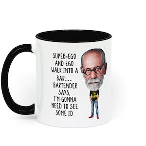 Könnte beinhalten: Eine weiße Keramiktasse mit schwarzem Rand und Henkel. Die Tasse zeigt eine Comic-Illustration eines Mannes mit Bart und Brille. Der Text auf der Tasse lautet "SUPER-EGO AND EGO WALK INTO A BAR... BARTENDER SAYS, I'M GONNA NEED TO SEE SOME ID".
