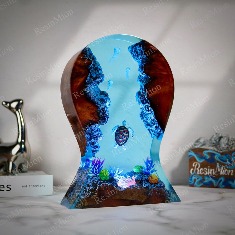 May include: A resin sculpture of a turtle swimming in a blue and turquoise ocean. The sculpture is made of wood and resin and has a light blue glow. The turtle is surrounded by coral and other sea life.