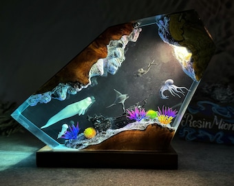 May include: A resin sculpture of an underwater scene with a white whale, a stingray, an octopus, and coral. The sculpture is lit from behind, creating a glowing effect.