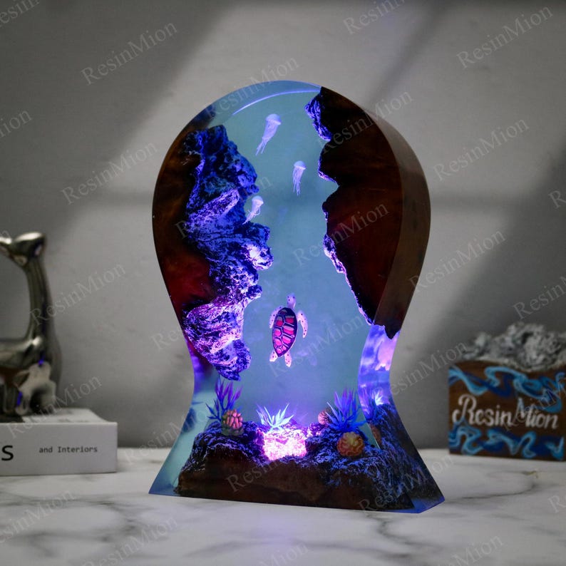 May include: A resin lamp with a blue and purple glow, featuring a sea turtle, jellyfish, and coral. The lamp is shaped like a teardrop and has a wooden base.