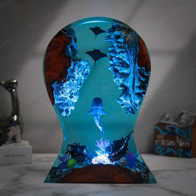 May include: A resin sculpture of a whale shark swimming in a blue ocean with coral reefs and two manta rays. The sculpture is illuminated from the bottom with a warm white light.