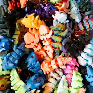 Puede incluir: Una colección de juguetes de plástico articulados de diferentes formas y colores. Los juguetes están hechos de plástico liso y brillante y tienen una variedad de diseños, incluyendo animales, insectos y formas abstractas.