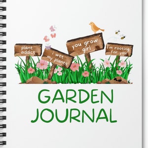 May include: A white spiral bound journal with a green title that reads "GARDEN JOURNAL". The cover features a whimsical illustration of wooden signs with gardening puns, including "plant addict", "I wet my plants", "you grow girl", and "I'm rooting for you".