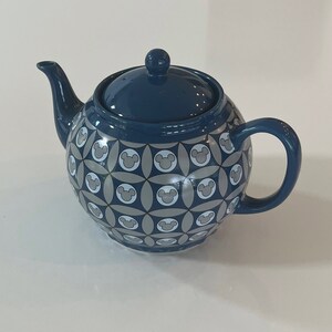 May include: A blue ceramic teapot with a Mickey Mouse pattern. The teapot has a lid and a handle.
