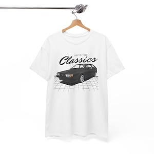 May include: White t-shirt with a black and white graphic of a classic car. The graphic says "Drive the Classics" and features a black Volkswagen Scirocco.