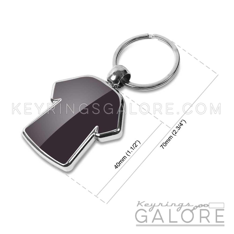 May include: A black and silver T-shirt shaped keychain. The keychain is 1.5 inches wide and 2.75 inches long. The text "KEYRINGSGALORE.COM" is visible. The keychain has a silver ring.