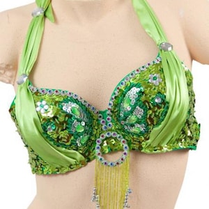 Op de afbeelding: Een groene paillettenbeha met een satijnen haltertop en een kralenfranje. De beha heeft een bloemenpatroon en is versierd met strass.