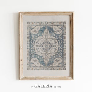 May include: A framed print of a vintage rug with a blue and white pattern. The rug has a floral design with a central medallion. The frame is a light wood color.