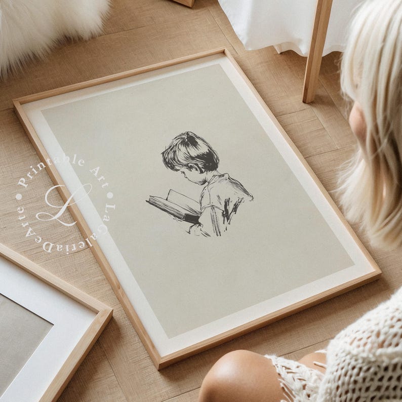 May include: A black and white illustration of a child reading a book. The illustration is printed on a light beige background and framed in a light wood frame.