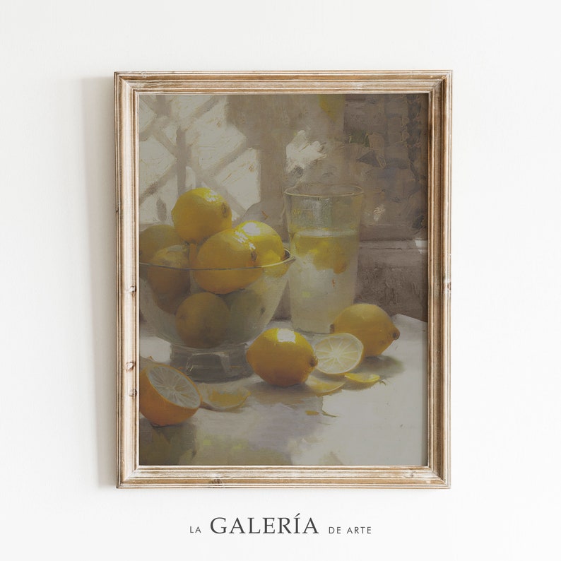 May include: A still life painting of a bowl of lemons, a glass of lemonade, and lemon slices on a white tablecloth. The painting is framed in a light wood frame.