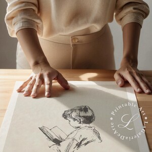 May include: A black and white illustration of a child reading a book. The illustration is on a white sheet of paper with a watermark of the text "Printable Art - La Galleria D'Arte".
