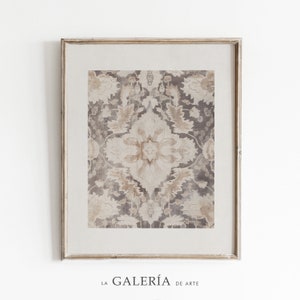 May include: A framed print of a vintage floral pattern in shades of beige and brown. The pattern is symmetrical and features intricate details. The frame is a light wood color with a distressed finish.