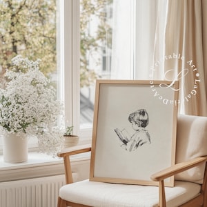 May include: A framed black and white illustration of a child reading a book. The illustration is on a beige background and the frame is a light wood color.