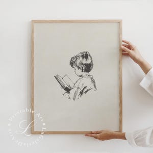 May include: A black and white illustration of a child reading a book. The child is sitting and looking down at the book. The illustration is framed in a light wood frame.