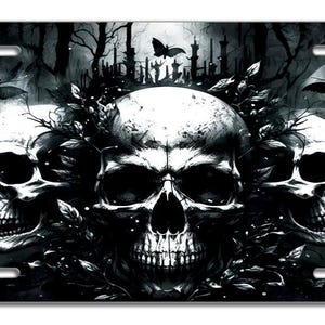 May include: Three black and white skulls with a dark background. The skulls are surrounded by black leaves and vines. There are small black bats flying around the skulls.