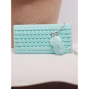 May include: A pair of novelty earrings featuring a light blue keyboard and mouse design. The keyboard has white lettering and numbers. The mouse has a scroll wheel and a button. The earrings are on a silver hook.