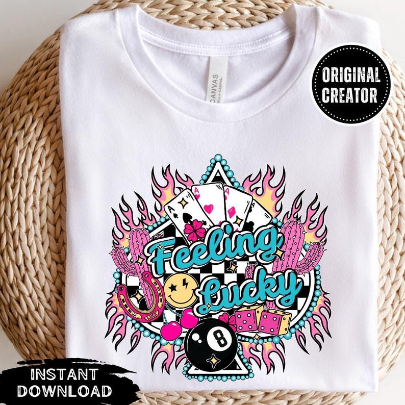 K&ouml;nnte beinhalten: Ein wei&szlig;es T-Shirt mit einem Grafikdesign eines brennenden Pik-Asses auf einem karierten Hintergrund und dem Text "Feeling Lucky". Das Design enth&auml;lt auch ein Hufeisen, ein Smiley, Kirschen und eine Billardkugel.