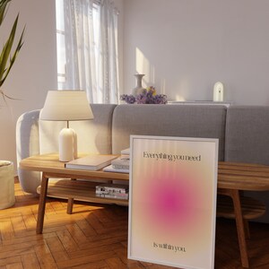K&ouml;nnte beinhalten: Gerahmtes Poster mit dem Text "Everything you need is within you" in einem wei&szlig;en Rahmen. Das Poster zeigt ein Farbverlauf-Design mit rosa und gelben Farbt&ouml;nen. Das Poster lehnt an einem Holzboden.