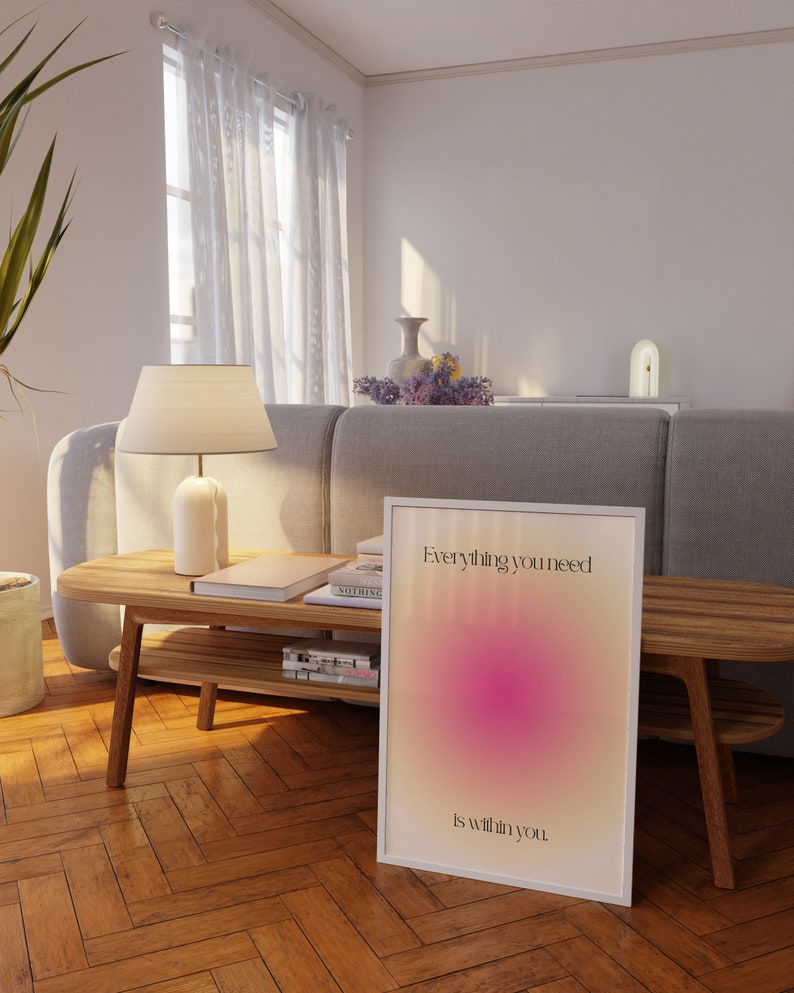 K&ouml;nnte beinhalten: Gerahmtes Poster mit dem Text "Everything you need is within you" in einem wei&szlig;en Rahmen. Das Poster zeigt ein Farbverlauf-Design mit rosa und gelben Farbt&ouml;nen. Das Poster lehnt an einem Holzboden.