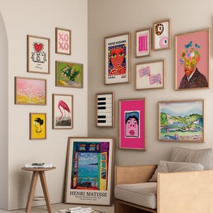Pode incluir: Uma parede de galeria com impress&otilde;es de arte emolduradas em v&aacute;rios tamanhos e estilos. A cole&ccedil;&atilde;o inclui arte abstrata, retratos e paisagens, com uma mistura de cores e temas. As impress&otilde;es s&atilde;o exibidas em uma parede neutra.