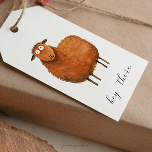 May include: A white gift tag with a brown sheep illustration and the text "hey there" in black calligraphy.