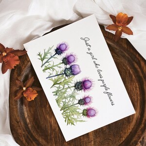May include: A white card with a watercolor illustration of purple thistle flowers and the text "Just a girl who loves purple flowers".