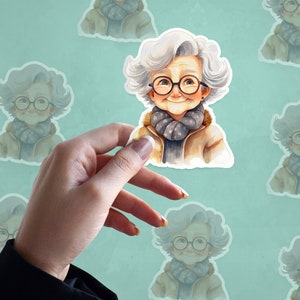 Peut inclure: Un autocollant repr&eacute;sentant une illustration &agrave; l'aquarelle d'une femme &acirc;g&eacute;e souriante aux cheveux gris, portant des lunettes, une veste marron et une &eacute;charpe grise.