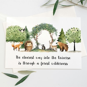 Peut inclure: Une illustration aquarelle d'une sc&egrave;ne de for&ecirc;t avec un renard, un h&eacute;risson, un blaireau, un cerf et un ours. Le texte "The clearest way into the Universe is through a forest wilderness" est &eacute;crit sous les animaux.