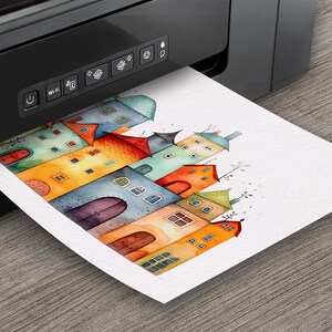May include: A printer printing a watercolor illustration of colorful houses on white paper.