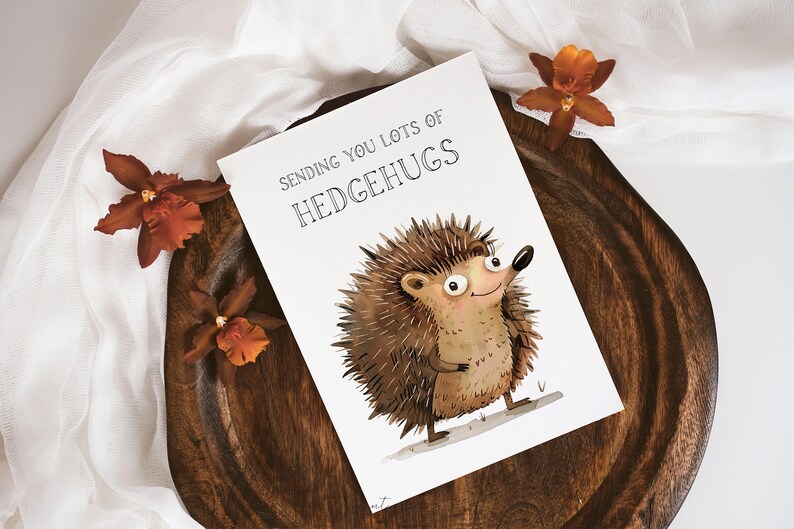 May include: A white card with the text "Sending you lots of Hedgehugs" and a cartoon illustration of a brown hedgehog with big eyes and a smile.