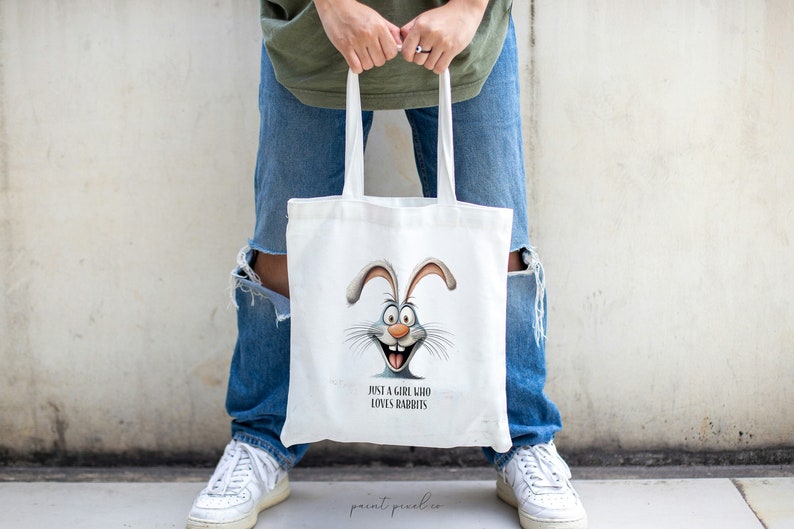 May include: A white tote bag with a cartoon bunny rabbit face and the text "Just a girl who loves rabbits".