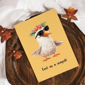 K&ouml;nnte beinhalten: Eine gelbe Karte mit einer Cartoon-Illustration einer wei&szlig;en M&ouml;we, die eine Sonnenbrille und eine Blumenkrone tr&auml;gt. Der Text "Cool as a seagull" ist auf der Karte gedruckt.
