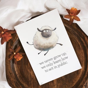 May include: A white sheep with black eyes and a black nose is jumping in the air. The sheep is on a white background with the text "we never grow up. we only learn how to act in public."