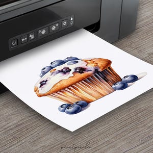 May include: A watercolor painting of a blueberry muffin with white frosting and blueberries on top. The muffin is sitting on a white background with more blueberries scattered around it.