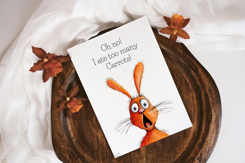 May include: A white card with an orange rabbit illustration and the text "Oh no! I ate too many Carrots!" The card is on a wooden surface with orange flowers.
