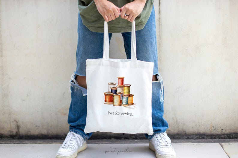 May include: White tote bag with a colorful illustration of spools of thread and the text "love for sewing".