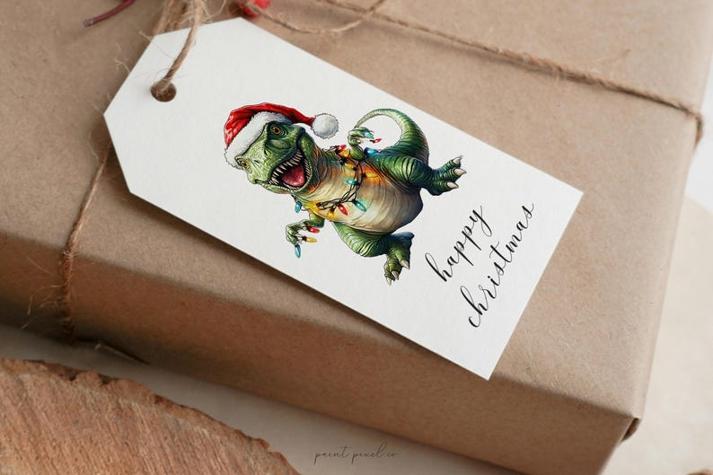 May include: A white gift tag with a green dinosaur wearing a red Santa hat and Christmas lights. The tag says "happy christmas" in black cursive writing.
