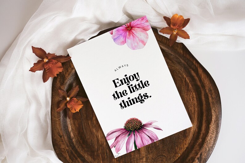K&ouml;nnte beinhalten: Eine wei&szlig;e Karte mit dem Text "ALWAYS Enjoy the little things." in Schwarz gedruckt. Die Karte ist mit rosa und violetten Aquarellblumen verziert und liegt auf einer Holzoberfl&auml;che.