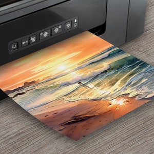 May include: A black printer with a control panel and a colorful sunset beach scene photo printing from the printer.