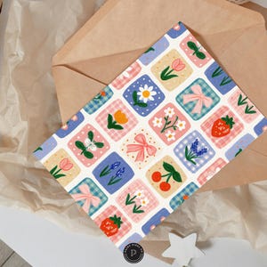 Puede incluir: Una tarjeta de felicitaci&oacute;n rectangular con un patr&oacute;n de cuadr&iacute;cula repetitivo de cuadrados. Cada cuadrado contiene una ilustraci&oacute;n diferente, incluyendo lazos rosas, fresas rojas, cerezas rojas, margaritas blancas, tulipanes y lavanda.