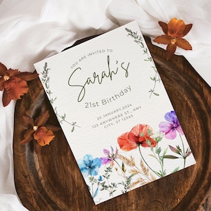 May include: A white invitation card with green lettering that reads "You are invited to Sarah's 21st Birthday" with a floral design featuring red, pink, blue, and white flowers. The date and address are printed below the text.