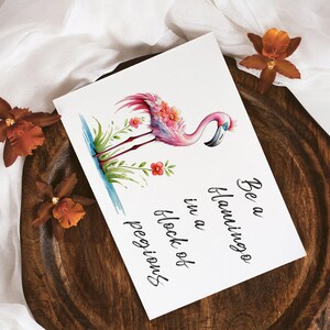 May include: A pink flamingo with flowers on its head stands in a pool of water. The text "Be a flamingo in a flock of peguins" is written below the flamingo.