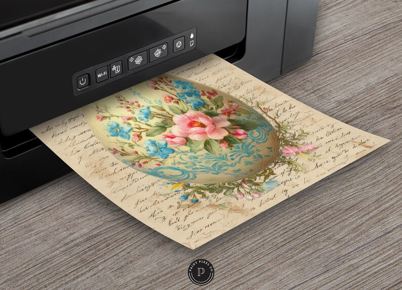 May include: A printed image of a decorative Easter egg with a floral design, featuring pink and blue flowers on a cream-colored background. The egg is printed on aged paper with handwritten script. A black printer is in the background.